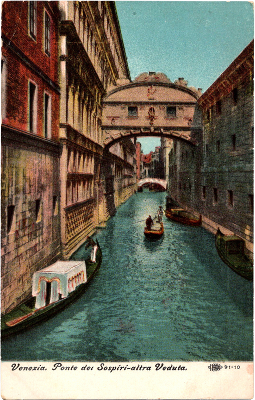 a water canal with boats and buildings under a bridge