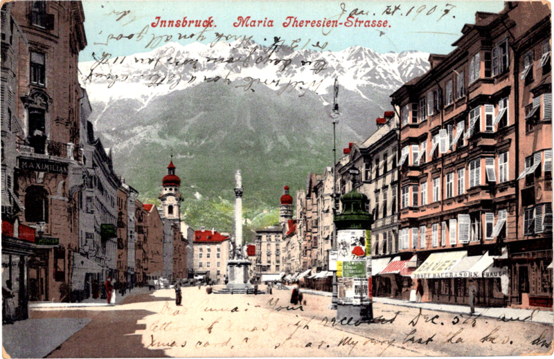 a city street with buildings and mountains in the background